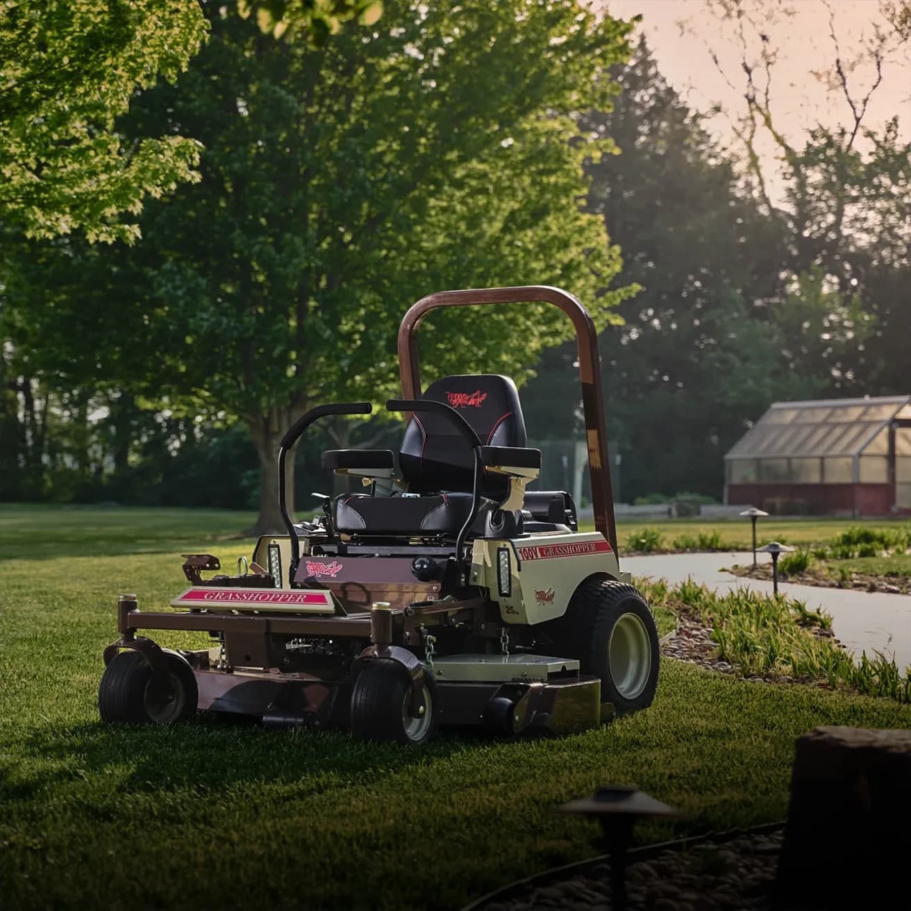 Two Grasshopper mowers parked side by side on a well-maintained grassy field in front of a modern building.